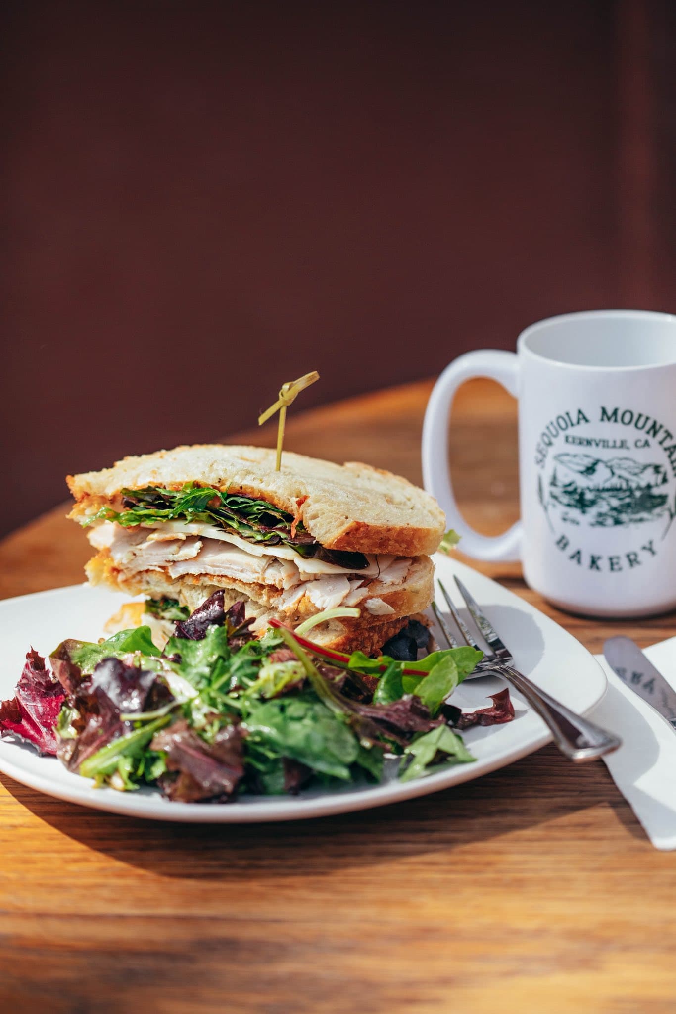 Sourdough club sandwich beside a Sequoia Mountain Bakery mug